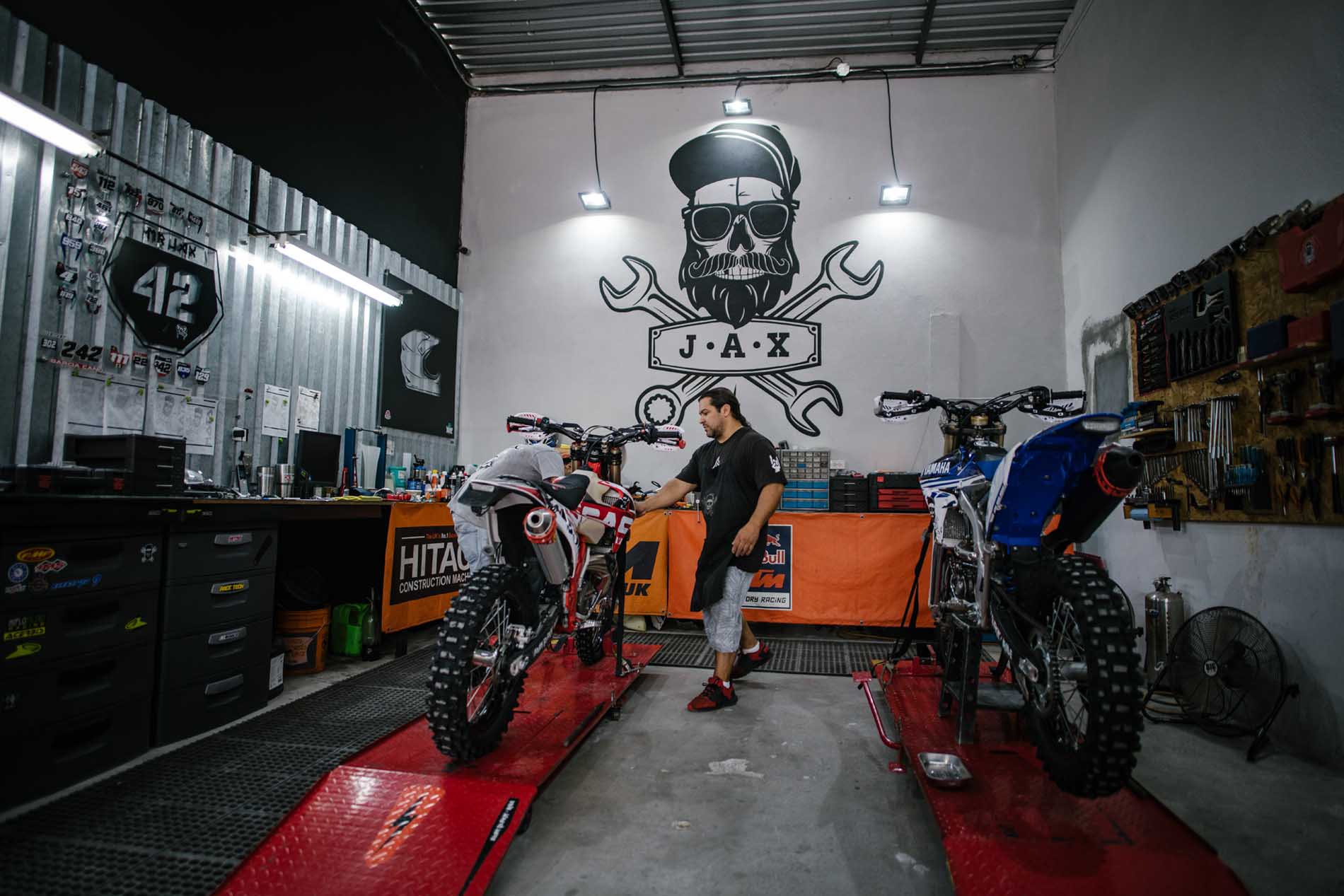Área de taller con un mecánico y motocicletas en elevadores